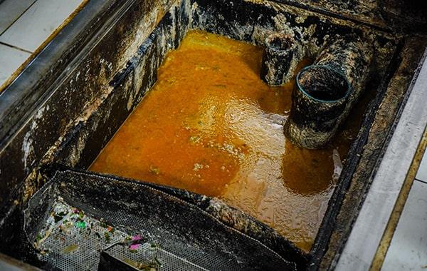 during grease trap cleaning, the trap is cleared, scraped, and washed to remove built-up grease and solids